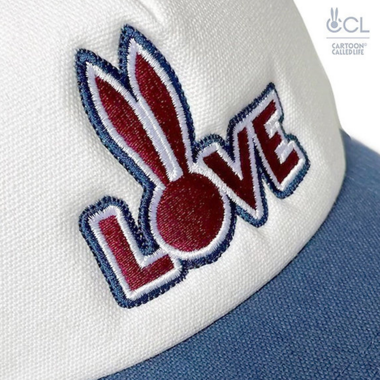 Wit, rood, blauwe truckers cap van Cartoon Called Life voorzien van 'Love' borduursel. Perfect voor gay mannen en verkrijgbaar bij Flavourez