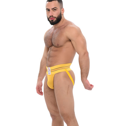 Gele jockstrap met Griekse details. Geïnspireerd op de jaren 70 en ontworpen door Sparta's Harness voor gay en queer mannen. Te koop bij Flavourez.