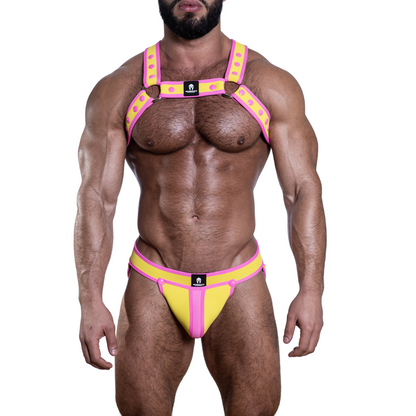 Een complete gay party outfit bestaande uit een geel harnas en jockstrap met roze drukknopen en biezen, ontworpen door het Italiaanse modehuis Sparta’s Harness en te koop bij Flavourez.